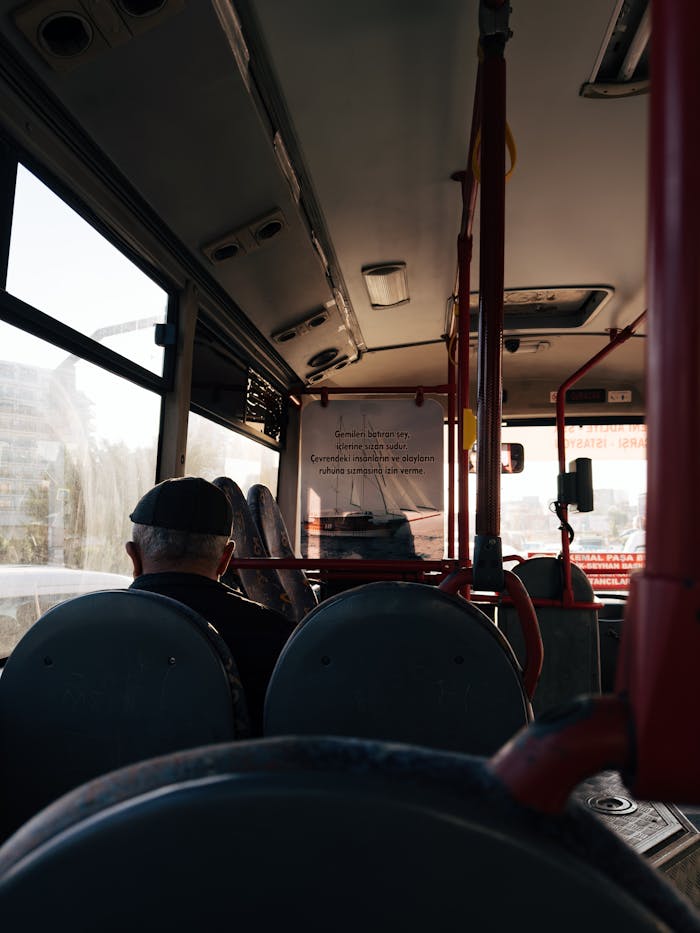 A thoughtful scene inside a public city bus with an older man by the window.